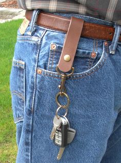 a person wearing jeans with a leather key chain attached to their waist and two keys in the back pocket