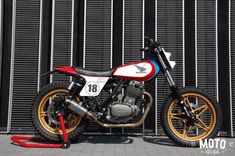 a red, white and blue motorcycle parked in front of a fence