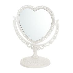 a white heart shaped mirror sitting on top of a metal stand with an ornate design