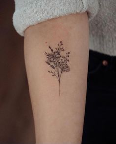 a small flower tattoo on the left arm