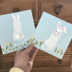 someone is holding up two cards with bunny images on them