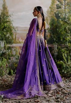 Editor's Note Introducing a captivating ensemble - a purple raw silk lehenga set paired with an organza base dupatta adorned with antique gold dori and intricate hand embroidery. This blend of traditional craftsmanship and modern design creates a stunning and elegant look, perfect for making a statement on special occasions. Fabric: Chanderi, organza Color: Purple Components: Blouse, lehenga and dupatta Closure: Hook & eye Embroidery details: Dori, aari & hand work Occasion: Sangeet Note: Produc Purple Lehenga Bridal, Lehanga Blouses Modern Design, Multicolour Lehenga, Cancan Lehenga, Purple Lehenga, Saree Hairstyles, Sangeet Outfit, Raw Silk Lehenga, Scallop Border