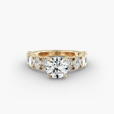 a yellow gold engagement ring with three stones on the side and an oval diamond center