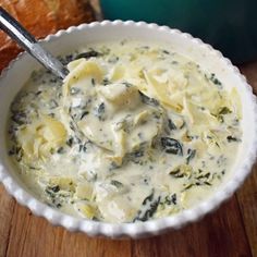 a white bowl filled with food next to bread