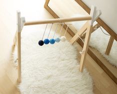 a wooden frame with three balls hanging from it's sides on a white rug