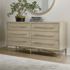 a wooden dresser sitting next to a mirror and potted plant on top of it