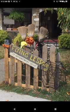 a wooden fence that has brooms on top of it and a sign reading flying less