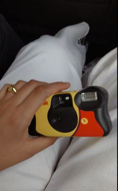 a hand holding a yellow and black object on top of a white sheet with pillows