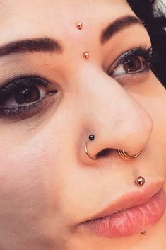 a close up of a woman with piercings on her nose and nose ring in front of her face