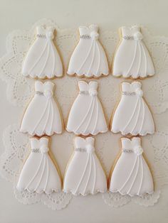 decorated cookies in the shape of brides dresses on a lace doily with white icing