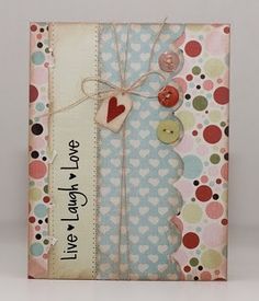 a card with buttons and hearts attached to the front, on a white background that says live laugh love