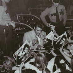 an old black and white photo of people signing autographs