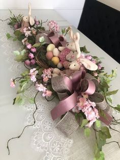 an arrangement of flowers and bunny figurines on a table with a lace doily