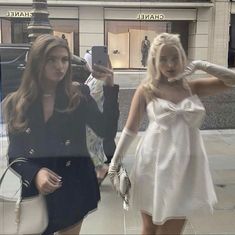 two women in short dresses and gloves walking down the street