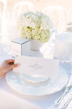 a table set with white plates and silverware, napkins and flowers on it