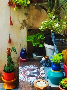 many potted plants are sitting on the ground in front of a wall with hanging decorations