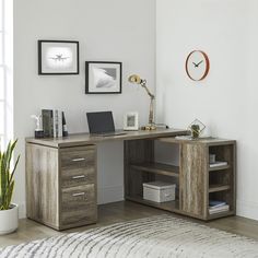 a desk with a laptop on it in front of a wall clock and pictures above it