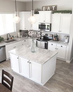 a large kitchen with white cabinets and marble counter tops, an island in the middle