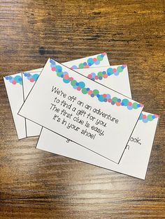 three envelopes with colorful confetti on them sitting on top of a wooden table