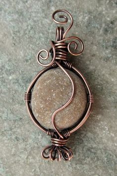 a wire wrapped pendant is sitting on the ground