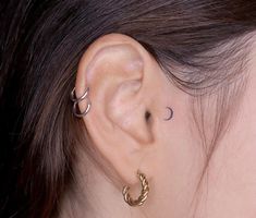 a close up of a person's ear with two small hoops attached to it