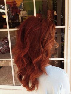 a woman with red hair is standing in front of a store window and looking out the window