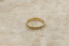 a gold ring sitting on top of a marble surface with small stones in the middle