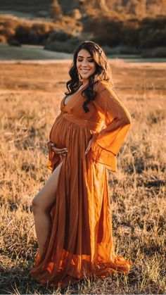 a pregnant woman in an orange dress posing for the camera