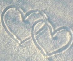 two hearts drawn in the snow on a sunny day