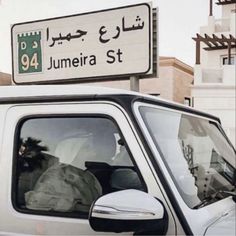 a white truck parked in front of a building with a street sign above the door