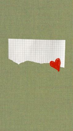 a piece of paper with a red heart in it on top of a green background