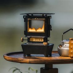 an old fashioned stove sitting on top of a wooden table next to a tea kettle