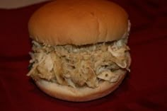 a close up of a sandwich on a red table cloth with meat and onions in it