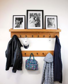 a coat rack with three pictures and two coats hanging on it's sides next to a purse