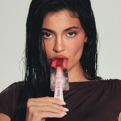 a woman with long black hair holding a tube of lipstick