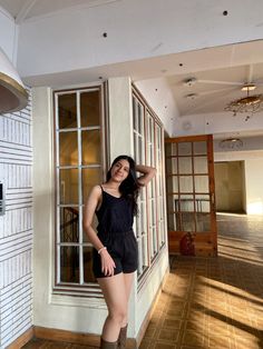 a woman standing in front of a window with her hand on her head while wearing boots