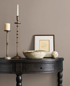 a wooden table with a bowl and two candles on it next to a framed photograph