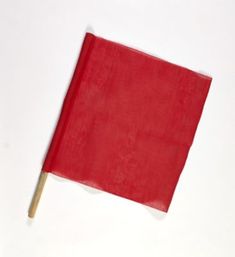 a red flag on a toothpick sticking out of the side of a white wall