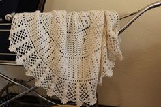 a white crocheted blanket sitting on top of a chair next to a wall