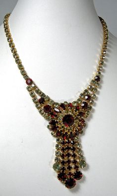 "I don't have too much information regarding this necklace. I know it's unusual because its rhinestones are red and grey. The necklace measures 16\" in length and the center drop measures 3\" long and 2\" at its widest point. It has a hook clasp in a gold tone setting.  This necklace is in excellent vintage condition." Red Rhinestone Necklaces For Evening, Red Rhinestone Evening Necklaces, Red Rhinestone Evening Necklace, Evening Red Rhinestone Necklace, Crystal Necklaces, Hook Clasp, Rhinestone Necklace, Red And Grey, Crystal Necklace