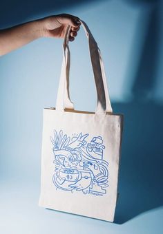 a hand holding a white bag with blue drawings on it