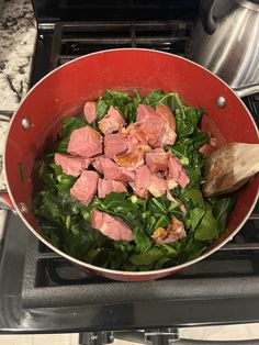 a pan filled with meat and greens on top of a stove