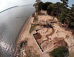 an aerial view of a beach with trees and sand in the foreground, looking down on it