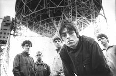 a group of men standing next to each other in front of a radio antenna with one man looking at the camera