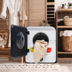 a washer sitting in the middle of a room next to some baskets and towels