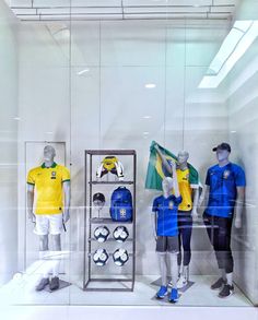 three mannequins wearing yellow and blue uniforms in a display case with soccer balls