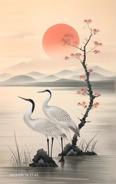 two birds are standing in the water near a tree with red flowers and mountains behind it