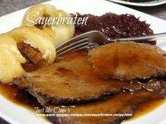 a white plate topped with meat covered in gravy next to bananas and cranberry sauce