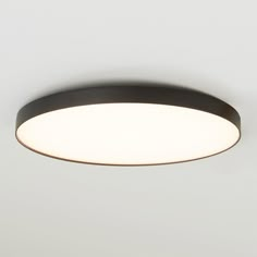 an overhead view of a circular light fixture with dim lighting on the ceiling and white walls in the background