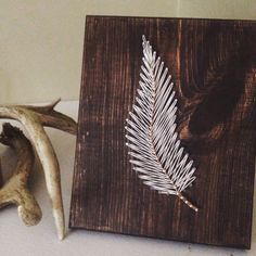 a piece of wood with a white leaf on it next to antlers and an antler